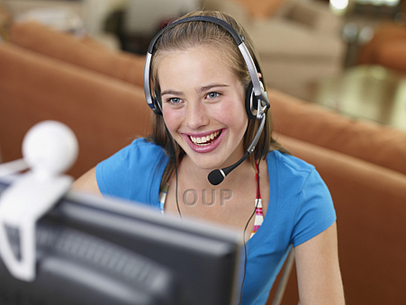 Young adult girl using a webcam and headset for video conferencing