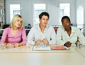 A woman and two men on an interview panel looking serious