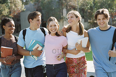 Group of teenagers walking in the sun holding books