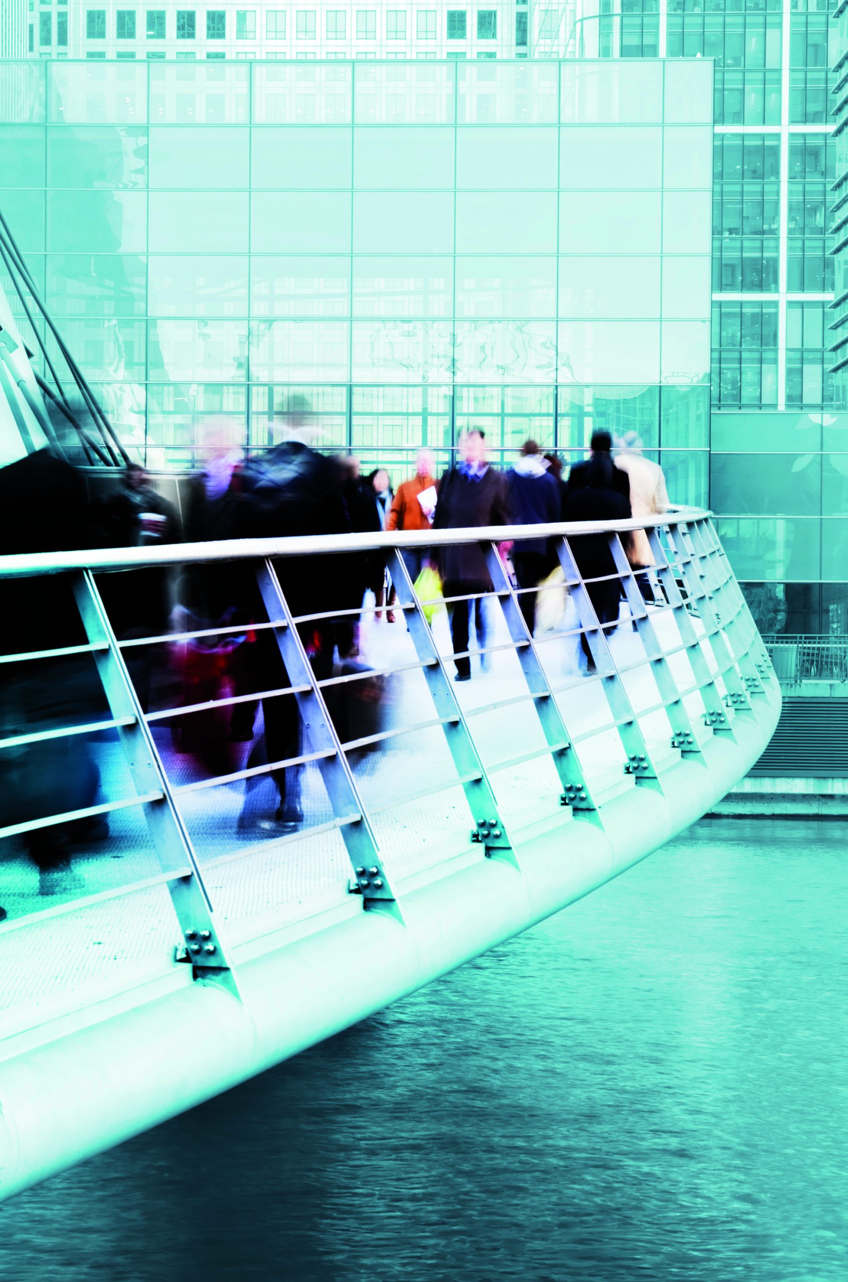Businessmen and women walking over a modern city bridge