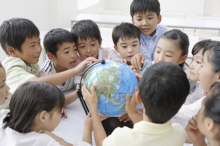 Group of oriental children crowding around a model globe