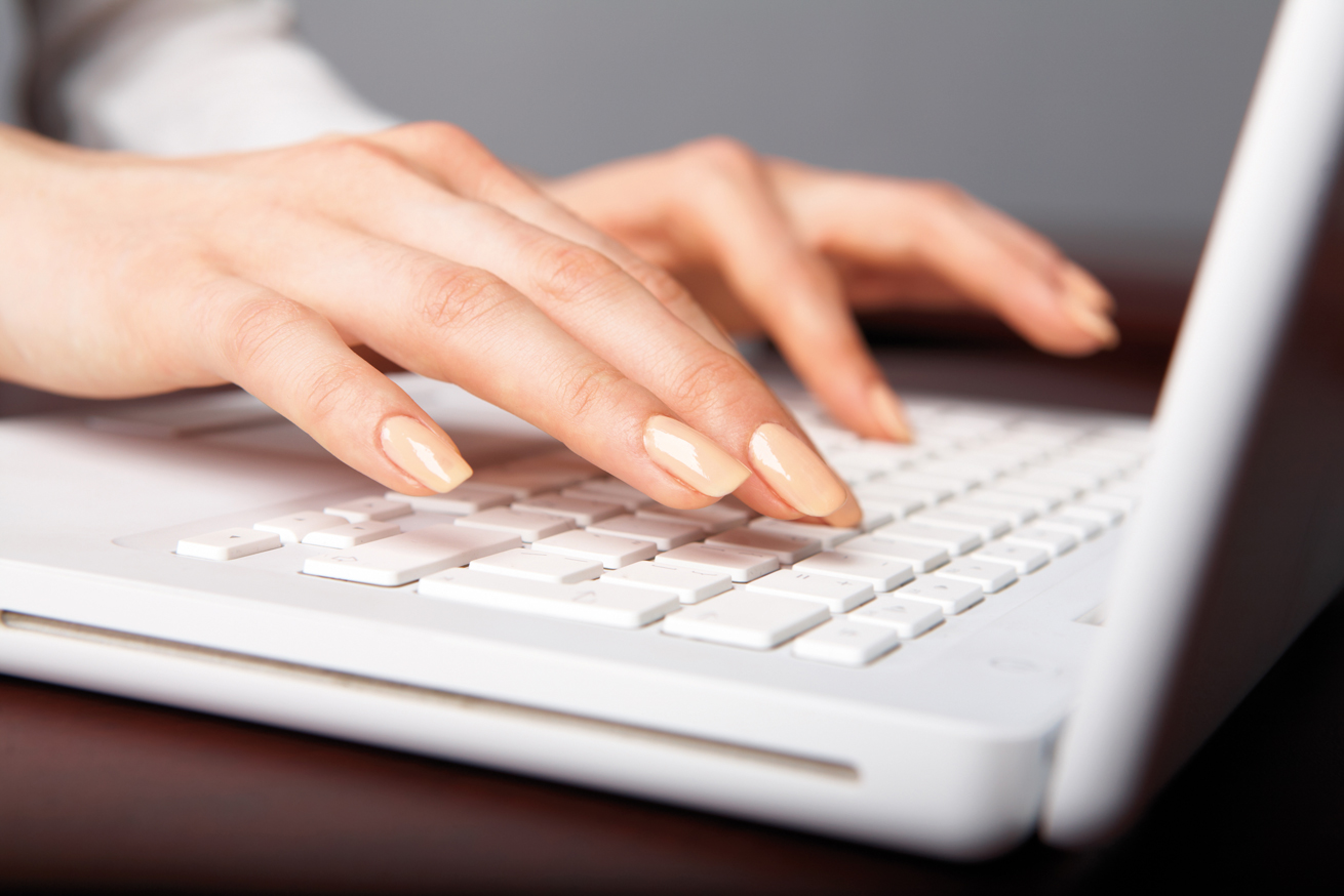 Woman's hands typing on a white laptop