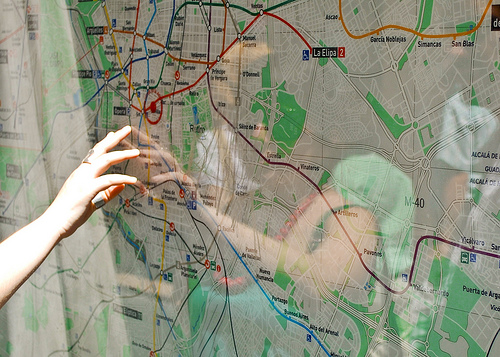 Wall-mounted map with woman pointing to a town