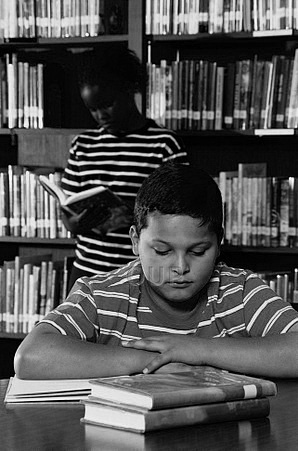Two young children reading in the library