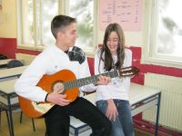 Student playing guitar with another student singing