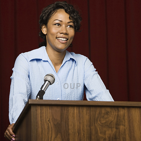 Mixed race businesswoman speaking at podium