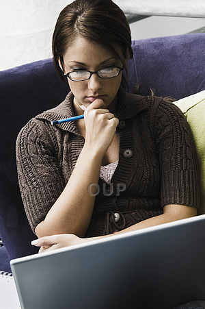Young woman thinking as she writes