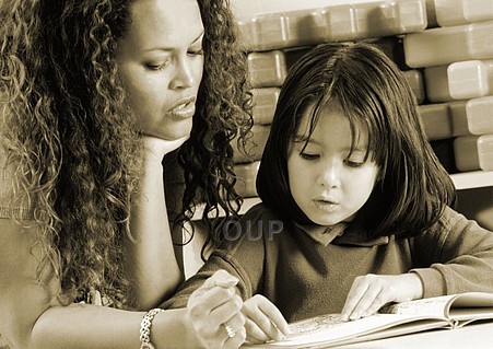 Teacher helping young girl to read