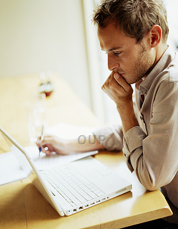 Young man thinking while using laptop