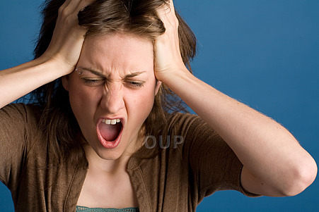 Young stressed woman holding her head and yelling.