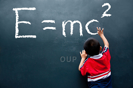 Young boy writing equation on chalkboard