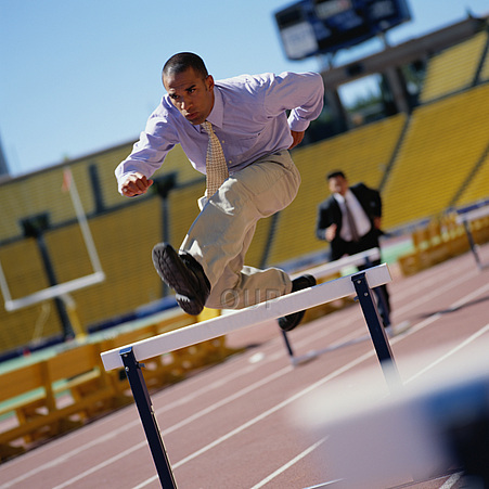 Businessman jumping over hurdles
