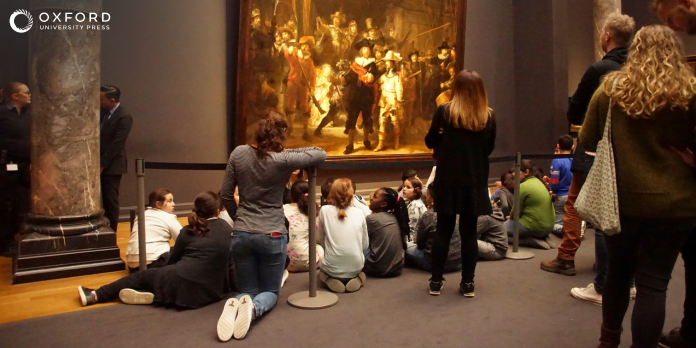 Students on a school trip at a museum, looking at a painting